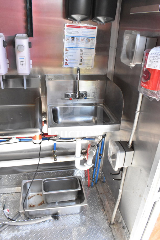 Interior view of 2022 Rock Solid Cargo food trailer featuring stainless steel sink, dispensers, and plumbing. Clean condition.