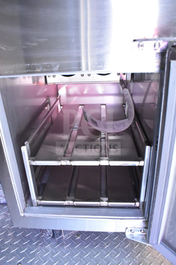 Interior view of 2022 Rock Solid Cargo 8.5x28 food trailer. Features shelving and stainless steel finish. Visible label inside.