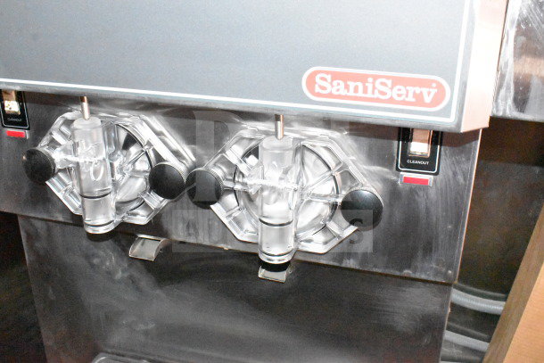 SaniServ ice cream machine with dual dispensers, stainless steel finish, and "Cleanout" switch.