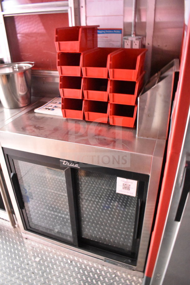 2022 Rock Solid Cargo 8.5x28 food trailer interior with True refrigeration unit, red stacking bins, stainless steel counter.