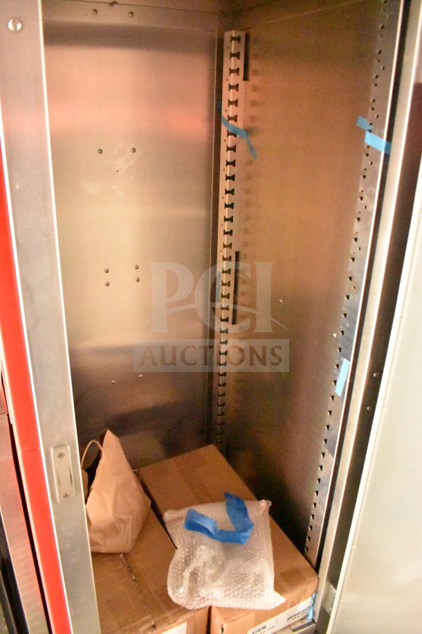 Inside view of 2022 Rock Solid Cargo food trailer, showing stainless steel interior with shelving mounts, cardboard boxes, and packaged items.