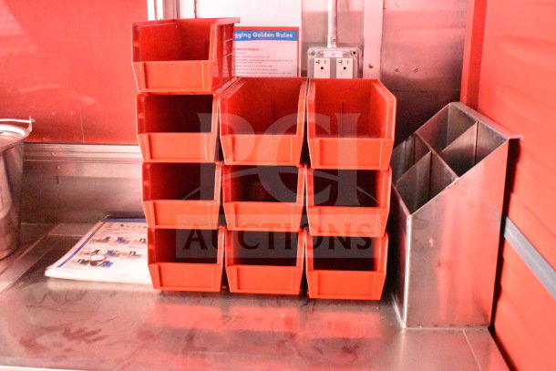 Red storage bins inside 2022 Rock Solid Cargo 8.5x28 food trailer, organized on a stainless steel shelf.