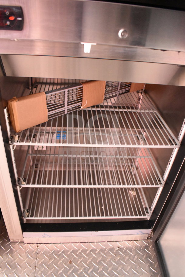 2022 Rock Solid Cargo 8.5x28 food trailer interior showing empty wire shelves and stainless steel refrigeration unit.