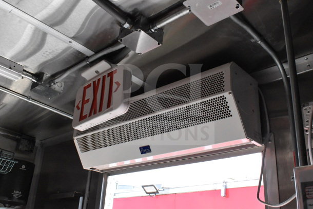 Interior of a 2022 Rock Solid Cargo 8.5x28 food trailer showing an EXIT sign and Amaco air curtain. Industrial metal finish.