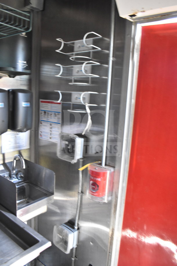 Titanium Cargo Trailers 8.5'x28' food trailer interior with sink, sanitizer dispenser, and fire safety equipment. Stainless steel walls.