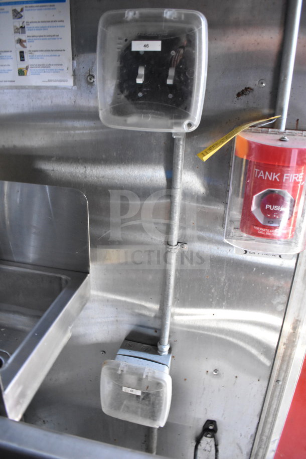 Inside view of Titanium Cargo food trailer showing metal wall, electrical outlet with cover, and fire extinguisher.