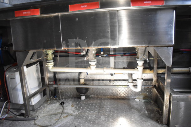 Stainless steel sink setup in Titanium Cargo Trailer for Wendy's food service, labeled for sanitize, rinse, and wash functions.