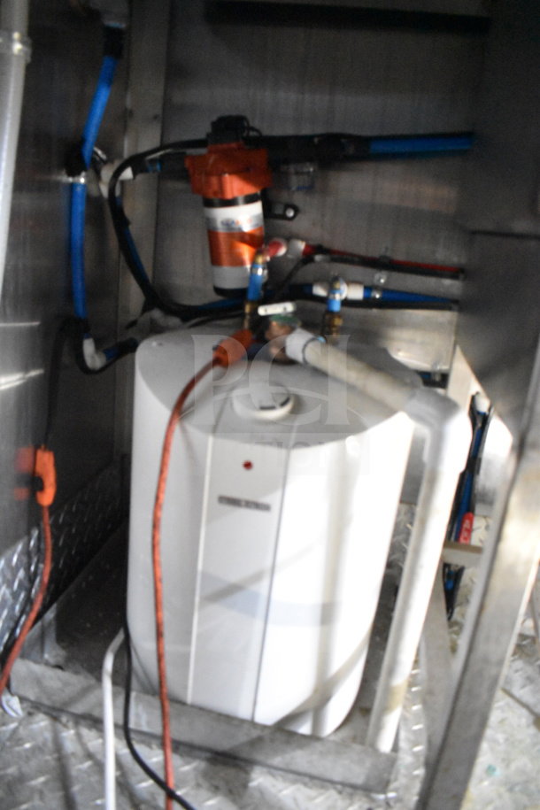 Interior view of a Titanium Cargo Trailers food trailer showing a system of pipes and a small water heater.