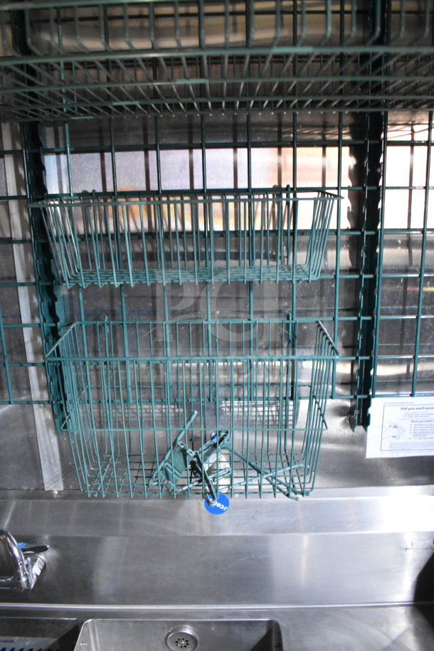 Stainless steel interior of a food trailer with green wire storage racks above a sink.