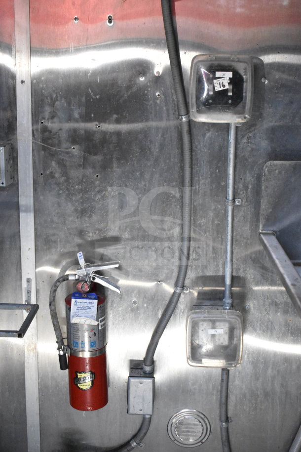 Titanium Cargo Trailers food trailer interior showing Buckeye fire extinguisher mounted on metal wall with wiring and outlets.