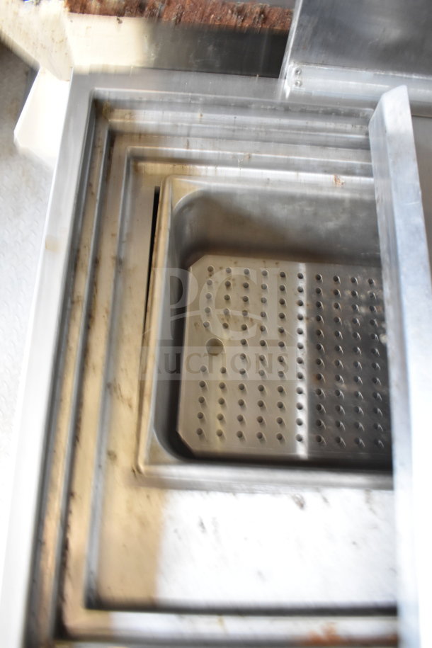 Stainless steel sink with perforated drain, part of food trailer kitchen equipment.