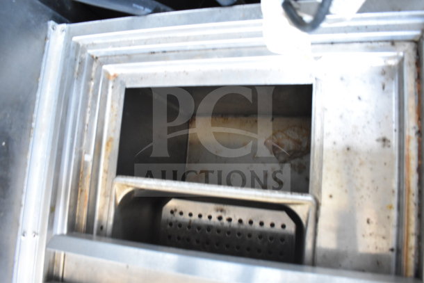 Interior of a food trailer's cooking equipment, showing a used metal compartment in fair condition with visible grease and residue.