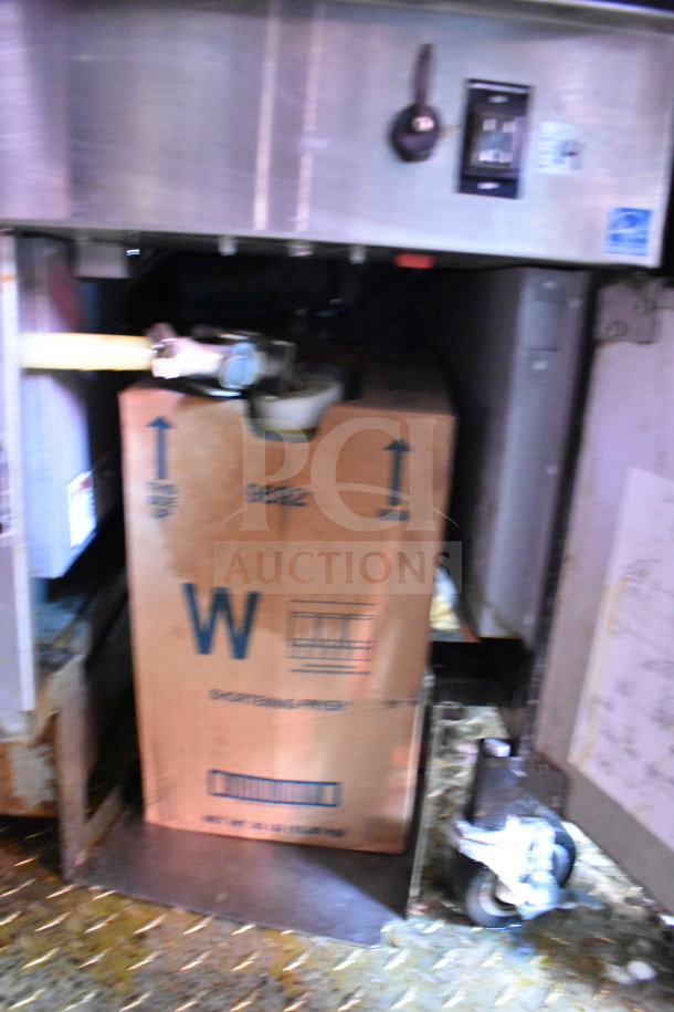 Titanium Cargo Trailers 8.5'x28' food trailer interior, showing cabinet with a cardboard box labeled "shortening filter" and industrial components.