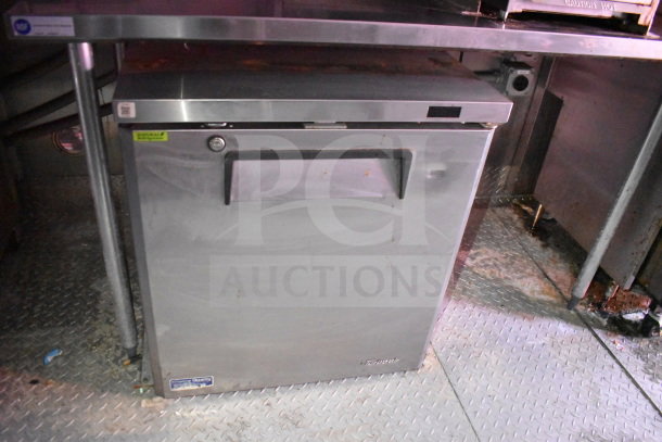 Stainless steel Turbo Air refrigerator in Titanium Cargo Trailer, visible model and quality label, placed on diamond plate flooring.