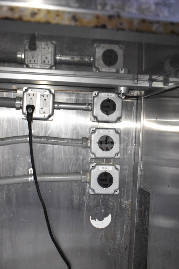 "Electrical outlets inside Titanium Cargo Trailer, featuring multiple labeled power sockets, essential for kitchen equipment."