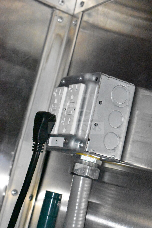 Electrical outlet with GFCI protection in Titanium Cargo Trailers' food trailer. Visible labeled “2” with cord plugged in.