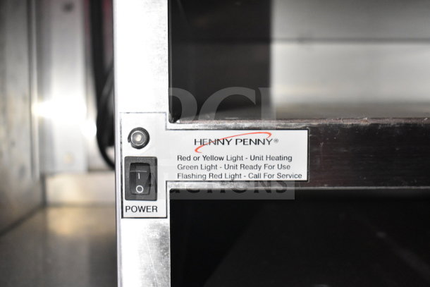 Close-up of a Henny Penny fryer control panel with a power switch and indicator light descriptions: heating, ready, and service alerts.