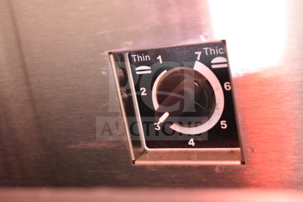 Close-up of a knob on a control panel with settings labeled "Thin" to "Thick" for food preparation adjustments.