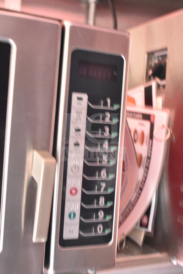 Control panel of a commercial microwave or kitchen appliance, featuring numbered buttons and a digital display.