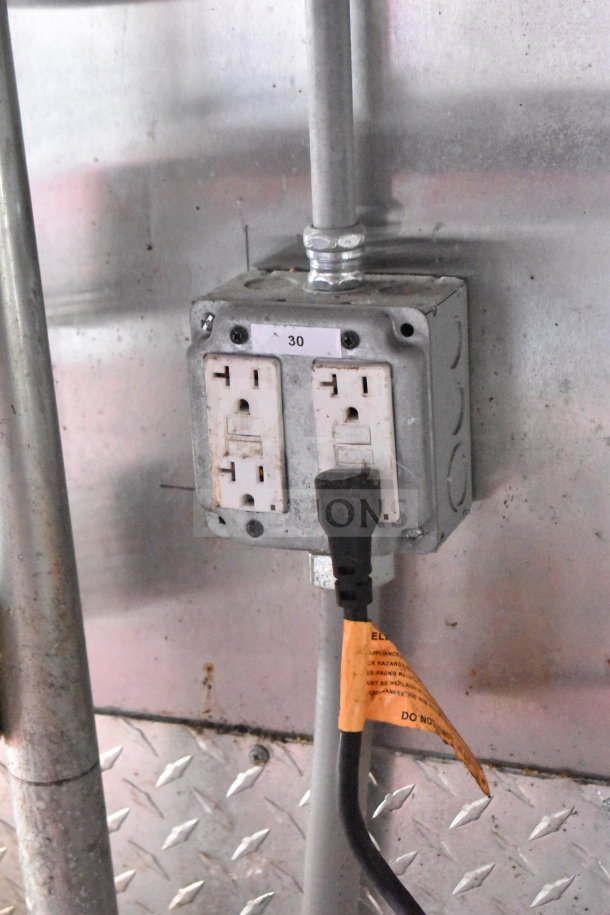 Electrical outlet with two sockets and a plug, labeled "30," inside a 2021 Titanium Cargo Trailer.