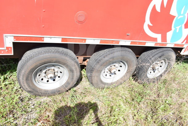 2021 Titanium Cargo Trailer side view, showing three wheels, part of Wendy's graphic, red exterior, in grassy area.