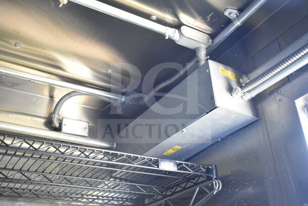 Interior view of a 2021 Diamond Cargo 8.5'x24' food trailer featuring a CaptiveAire grease hood, wiring, and storage rack.
