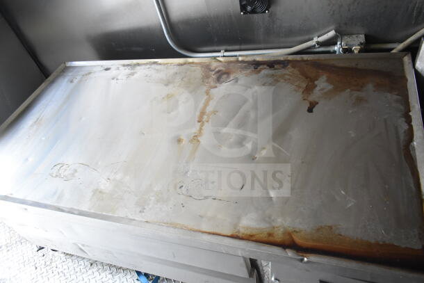 Interior view of used 2021 Diamond Cargo 8.5'x24' food trailer showing a stainless steel countertop with wear and grease stains.