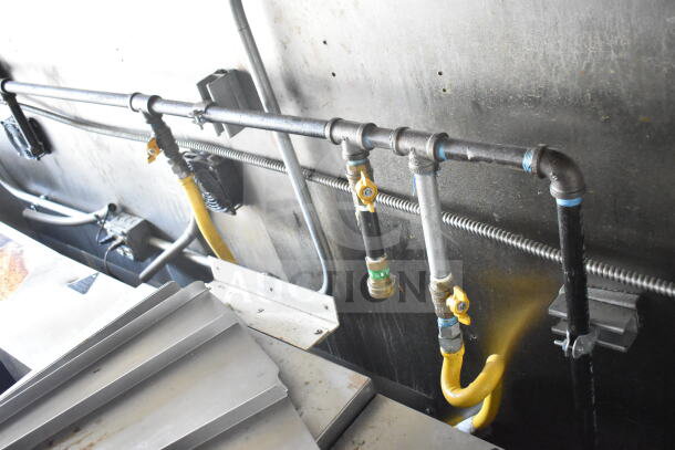 Interior view of a 2021 Diamond Cargo 8.5'x24' food trailer showing plumbing and gas lines, featuring CaptiveAire grease hood.