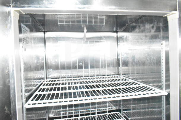 Interior view of the 2021 Diamond Cargo food trailer's stainless steel refrigeration unit with wire shelves.