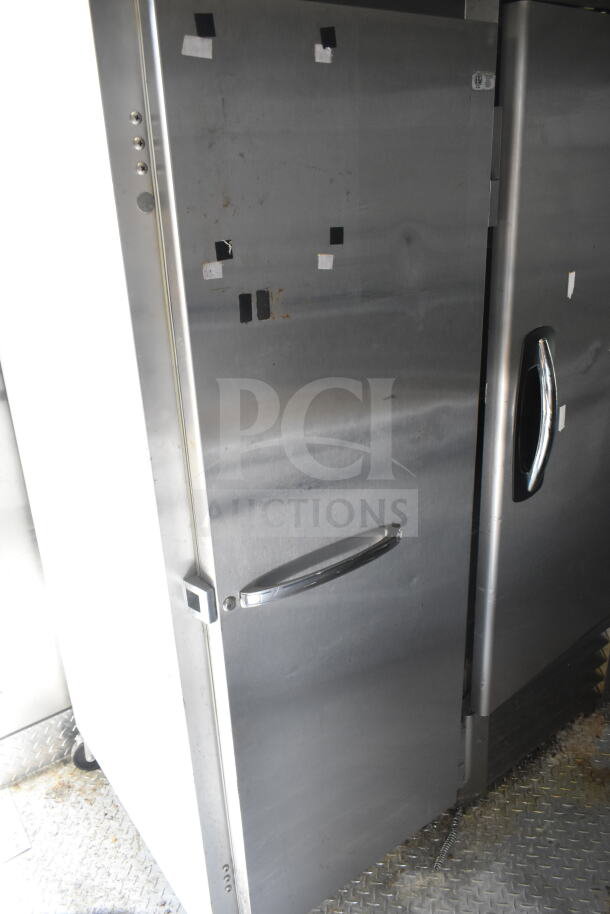 Stainless steel refrigerator inside a 2021 Diamond Cargo food trailer. Visible wear and markings indicate previous use.