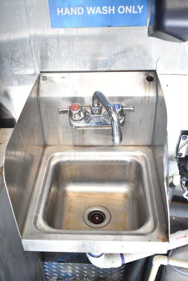 Stainless steel hand wash sink with hot and cold faucets, labeled NSF, in Diamond Cargo food trailer.
