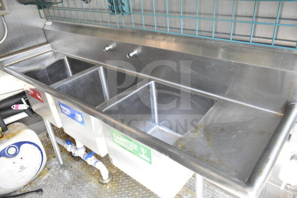 Stainless steel triple sink in 2021 Diamond Cargo 8.5'x24' food trailer, labeled for wash, rinse, sanitize.