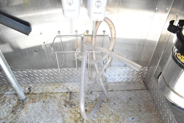 Interior of a 2021 Diamond Cargo food trailer featuring utility hoses, metal shelves, and diamond plate flooring with visible wear.