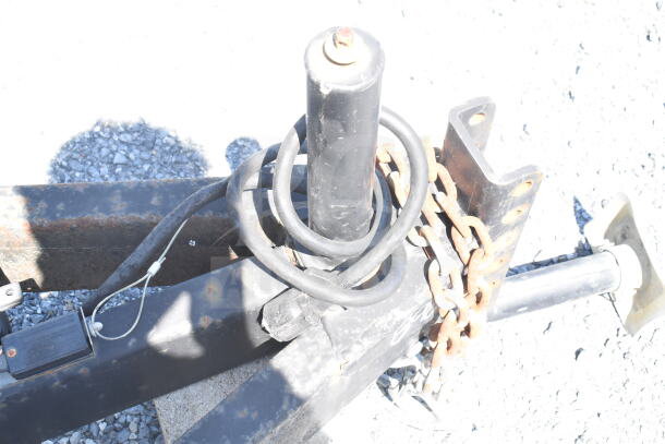 Trailer hitch of a 2021 Diamond Cargo food trailer, showing chains and cables, in used condition on gravel surface.