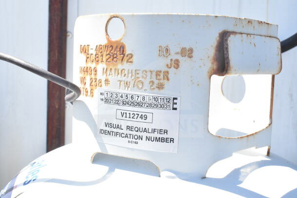 Rusted label on a propane tank, showing specifications and a visual requalifier identification number, V112749.