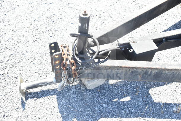 Diamond Cargo trailer hitch with lock, chains, and wiring on gravel. Rust visible, indicating wear. Model: 8.5'x24'.