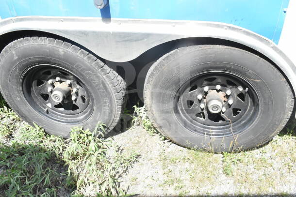 Dual tires of a 2021 Diamond Cargo 8.5'x24' food trailer; rims show wear from outdoor use.