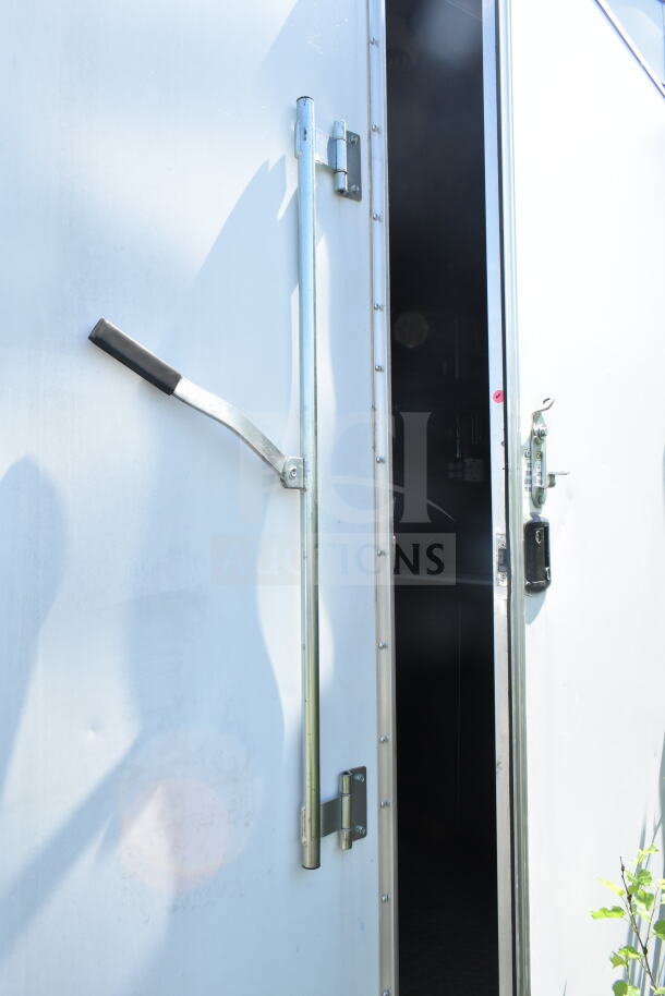 Exterior view of a partially open 2021 Diamond Cargo 8.5'x24' food trailer. Metal handle and hinges visible on white door.