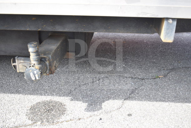 Close-up view of a trailer's hitch attachment on pavement, part of a 2021 Texino 28ft cooking trailer, VIN: 4B9T1EC3XMM286019.