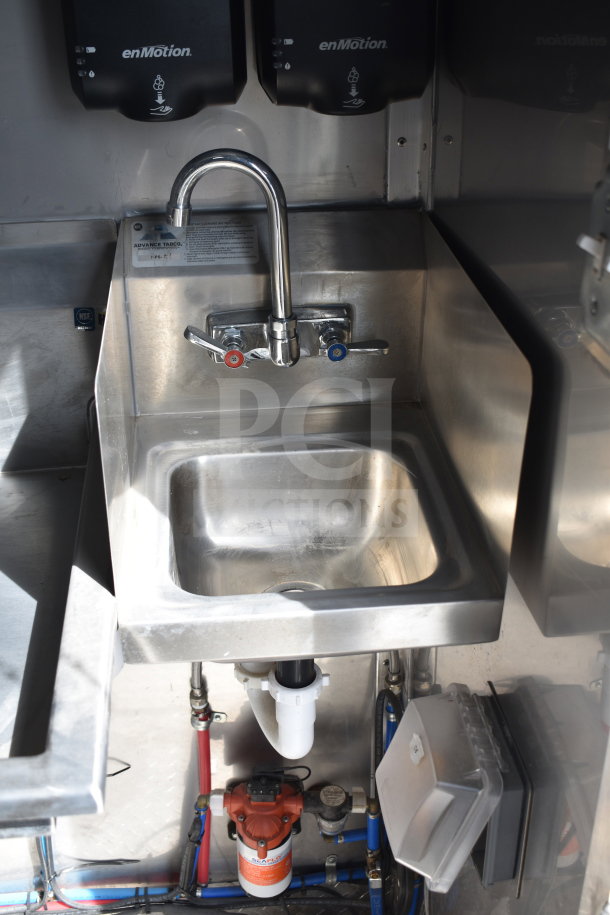 Stainless steel sink in a 2021 Texino cooking trailer with dual-lever faucet and enMotion soap dispensers above.