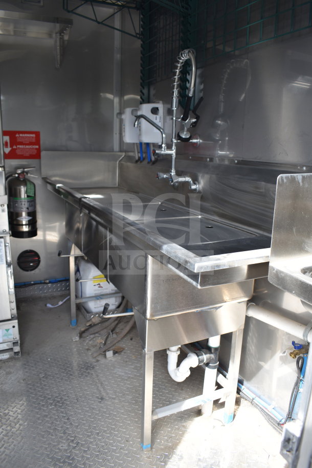 Interior of a 2021 Texino 28ft triple-axle cooking trailer with stainless steel countertops, sink, and industrial faucet.