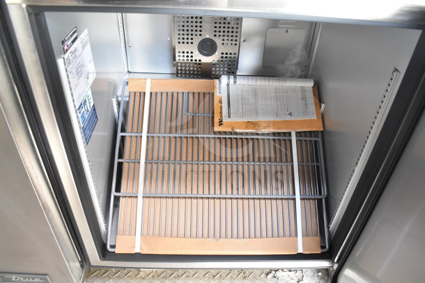 Inside view of new 2021 Texino cooking trailer cabinet with a rack, inspection paper, and Winston CVap holding unit manual.