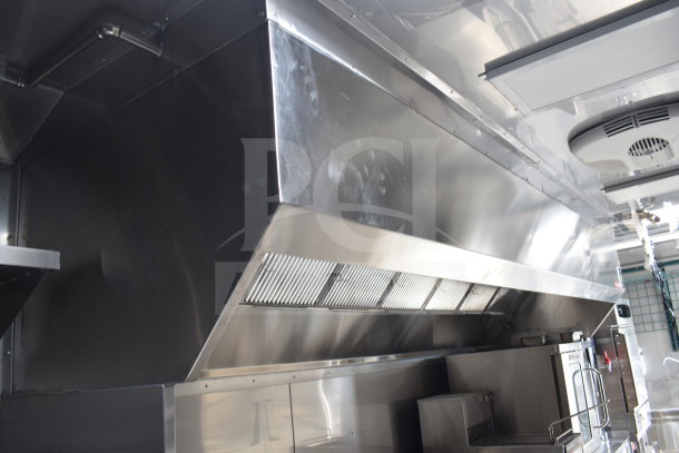 Interior view of Texino 28ft cooking trailer showing CaptiveAire hood system and modern stainless-steel appliances.