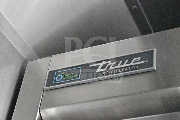 Close-up of True Refrigeration logo on a stainless steel surface, indicating use of natural refrigerant technology.