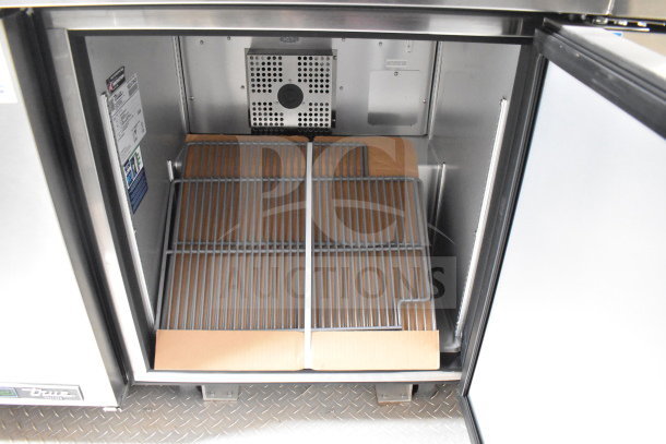 Interior view of True refrigeration unit in a 2021 Texino 28ft cooking trailer, featuring wire shelving and cooling unit.