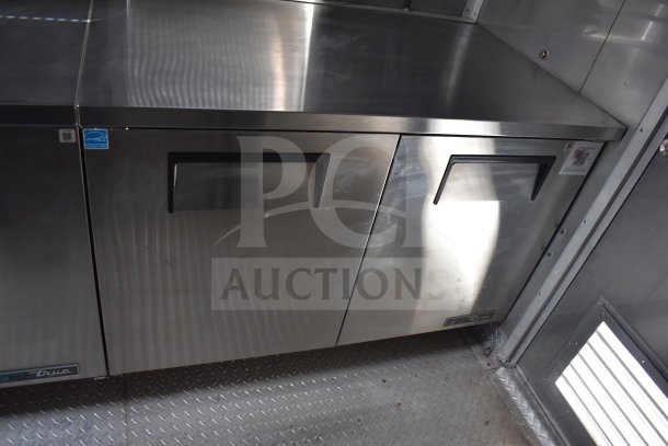 Texino cooking trailer with stainless steel True refrigeration suite, dual doors, and diamond plate flooring.