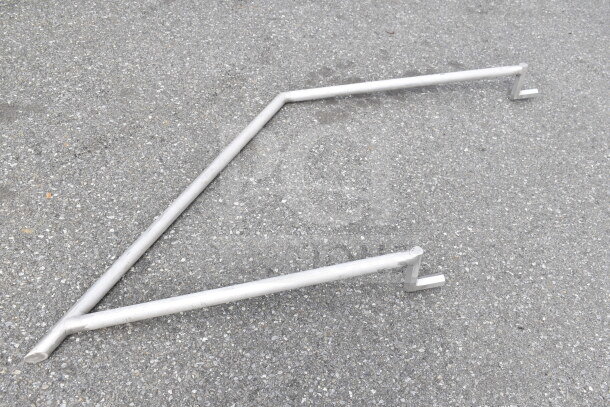 Metal pipe frame on pavement, showcasing a simple geometric design with angled joints and flat ends.