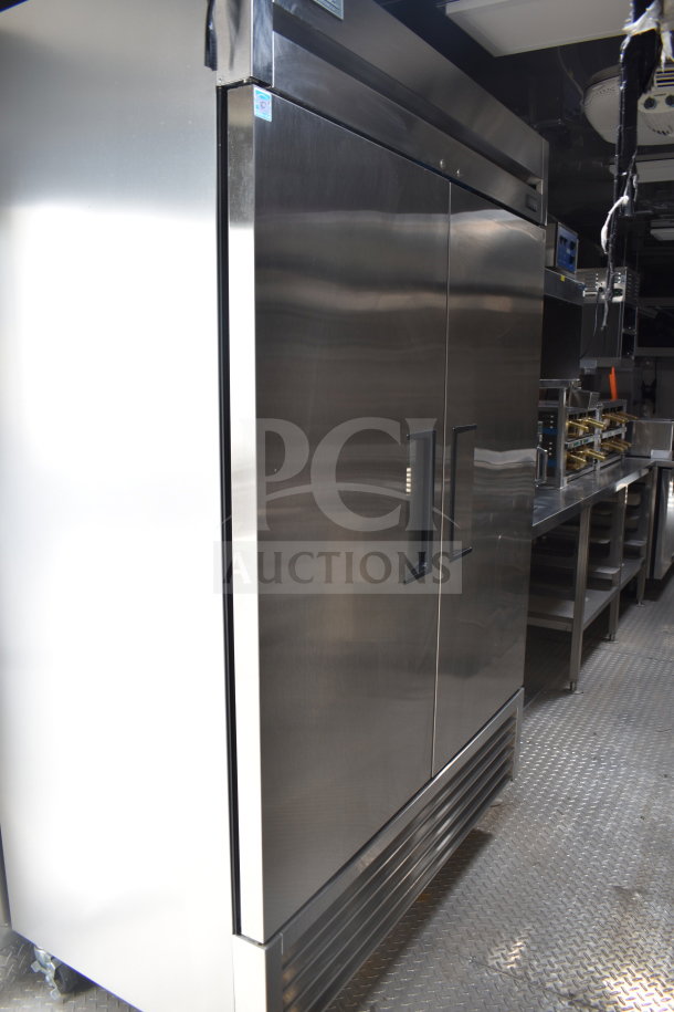 2021 Texino 28ft cooking trailer interior showing a stainless steel True refrigeration unit next to cooking equipment.