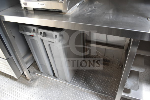 Interior view of Texino cooking trailer showing stainless steel prep counter and gray waste bins beneath.