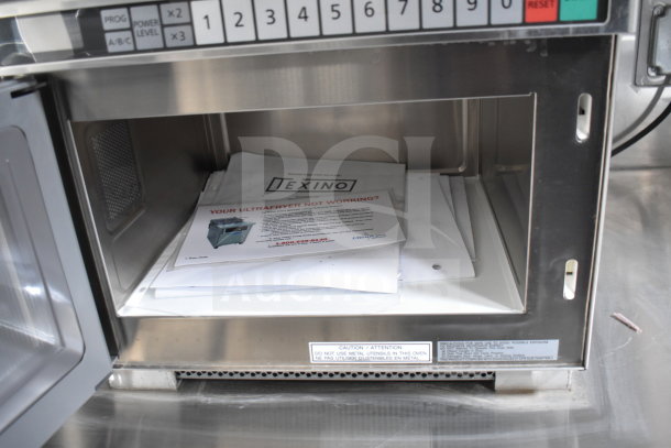 Open stainless steel microwave showing Texino documents related to Ultrafryer maintenance inside.